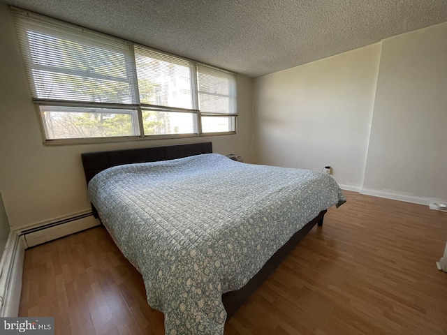1030 E Lancaster Ave Unit 227, Bryn Mawr, PA 19010 - bedroom featuring wood finished floors, a textured ceiling, baseboards, and a baseboard heating unit