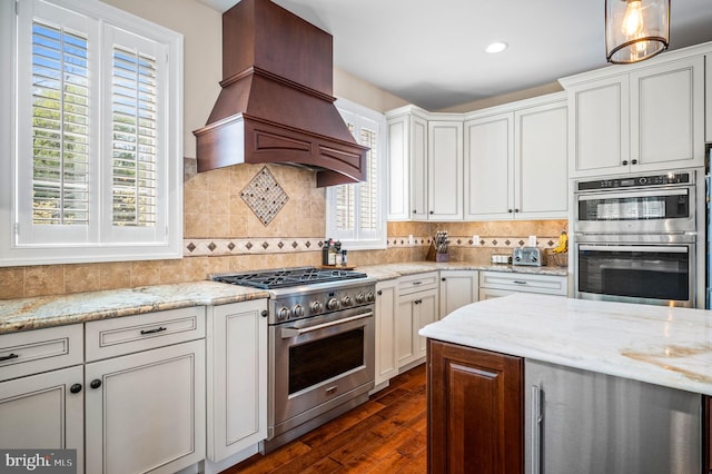 211 Dutton Mill Rd, West Chester, PA 19380 - kitchen featuring appliances with stainless steel finishes, premium range hood, dark wood-type flooring, backsplash, and light stone counters