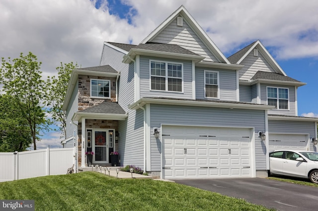 view of front of home featuring an attached garage, driveway, stone siding, and a shingled roof