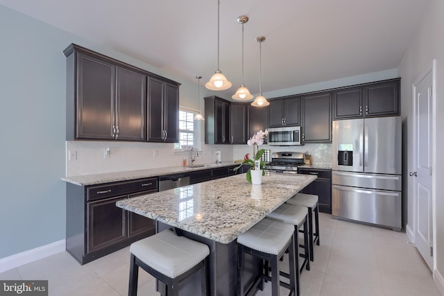 kitchen with appliances with stainless steel finishes, light stone countertops, a breakfast bar area, and decorative backsplash