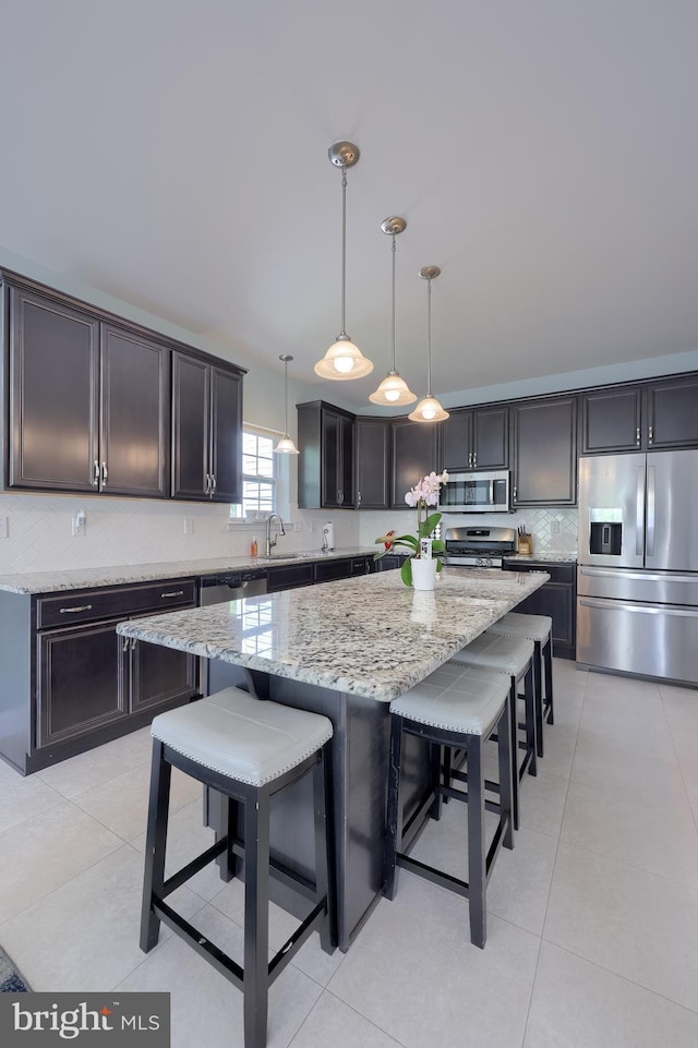 kitchen with stainless steel appliances, a sink, backsplash, a kitchen island, and a breakfast bar