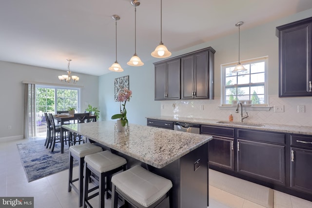 kitchen with a sink, stainless steel dishwasher, backsplash, and light stone countertops