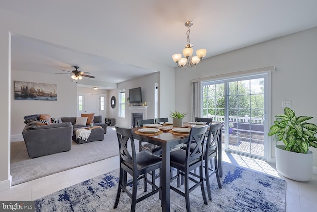 dining space with a fireplace, tile patterned floors, a chandelier, and baseboards
