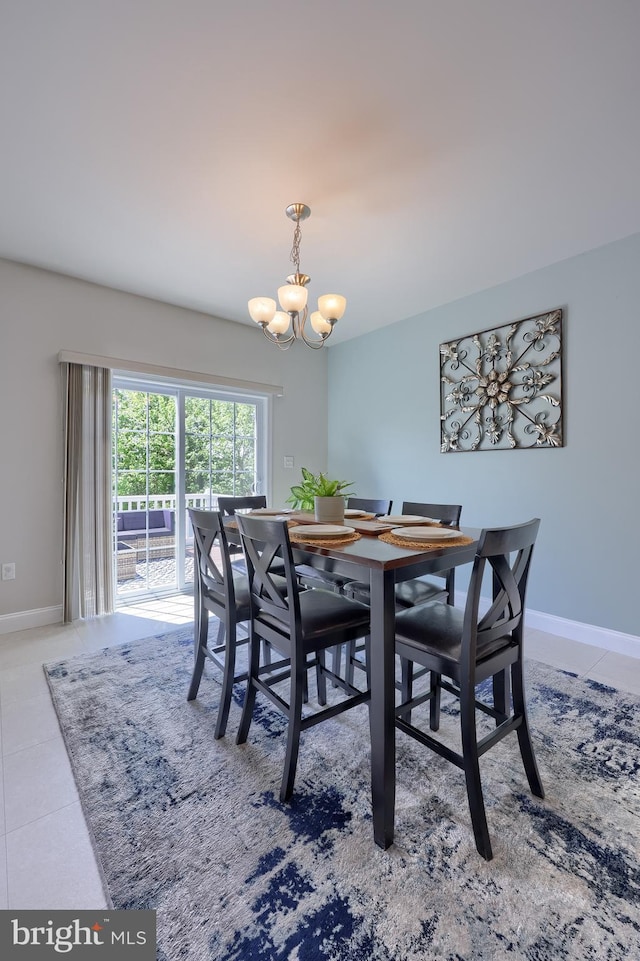 dining area featuring a chandelier, tile patterned flooring, and baseboards