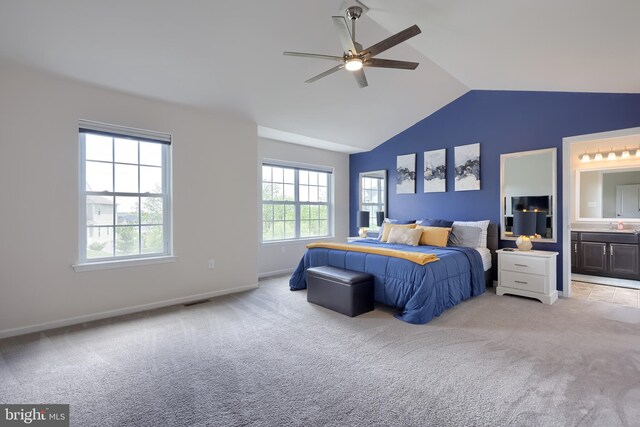 bedroom featuring carpet floors, vaulted ceiling, ensuite bathroom, baseboards, and a ceiling fan