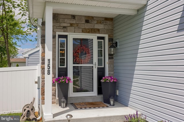 property entrance featuring stone siding and fence