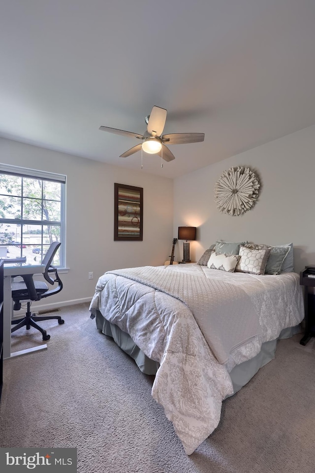 carpeted bedroom featuring a desk, a ceiling fan, and baseboards