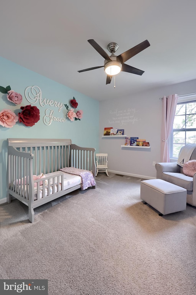 bedroom with carpet floors, a crib, baseboards, and a ceiling fan