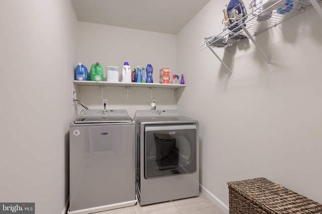 laundry room with separate washer and dryer, light tile patterned flooring, and baseboards