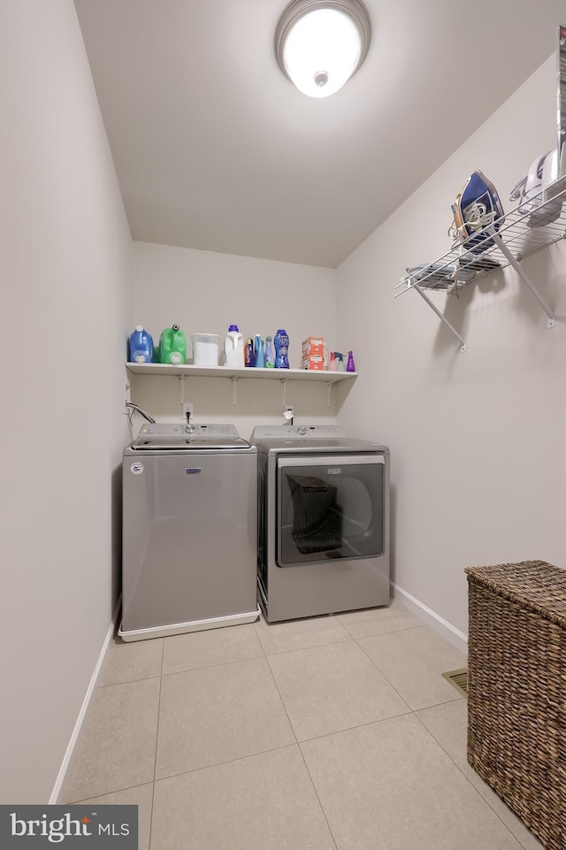 clothes washing area featuring washer and dryer, baseboards, and tile patterned flooring