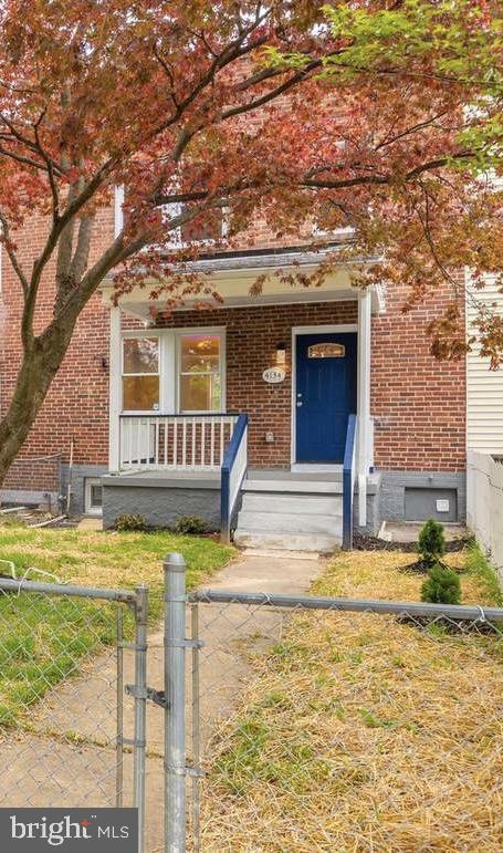 4134 Woodhaven Ave, Baltimore, MD 21216 - view of front of house featuring a porch, brick siding, a fenced front yard, and a gate