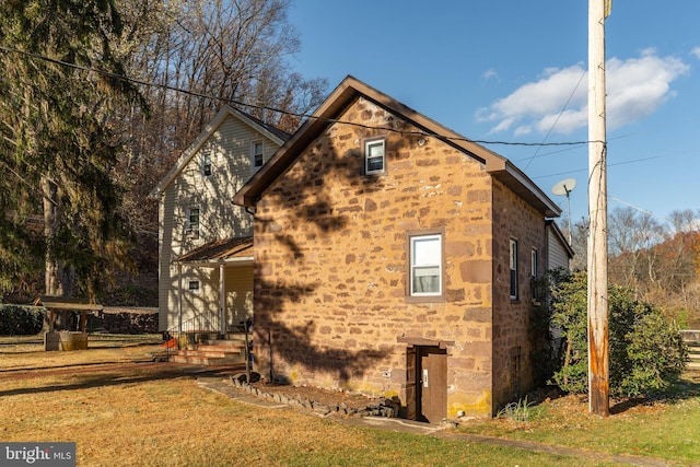 view of side of home with a lawn and stone siding