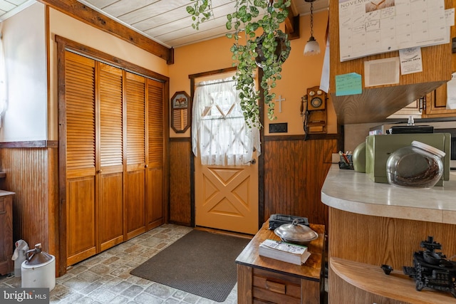 foyer with a wainscoted wall, wood walls, and light stone finish floors