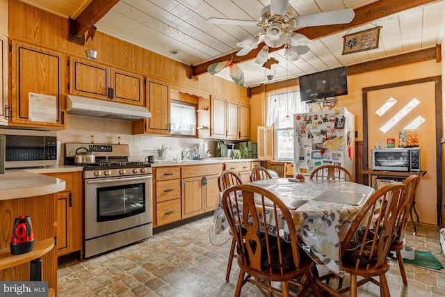kitchen with appliances with stainless steel finishes, under cabinet range hood, ceiling fan, light countertops, and wood ceiling