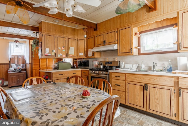 kitchen with under cabinet range hood, stainless steel appliances, a sink, beamed ceiling, and light countertops