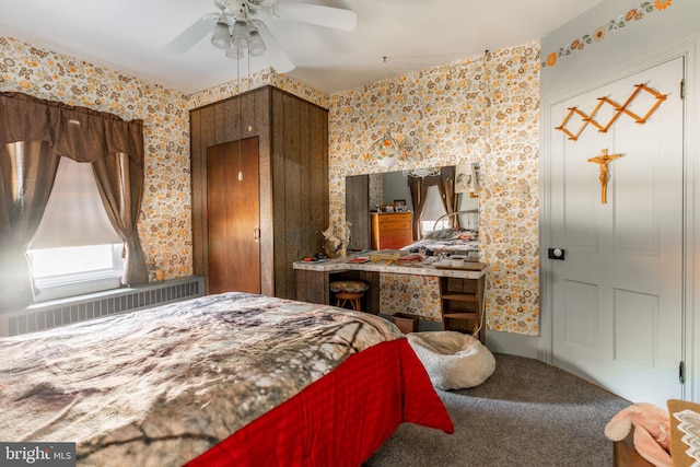 carpeted bedroom with wallpapered walls, radiator, and ceiling fan