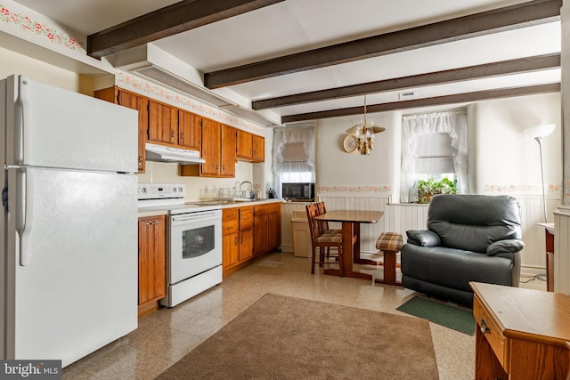 kitchen with white appliances, under cabinet range hood, wainscoting, brown cabinetry, and light countertops
