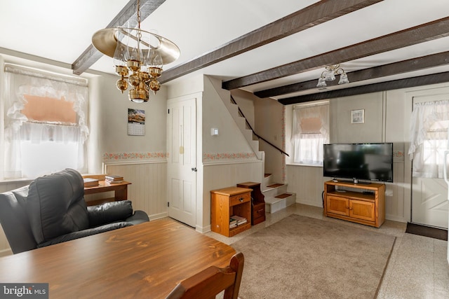 living room with wainscoting, stairs, a chandelier, beamed ceiling, and baseboards