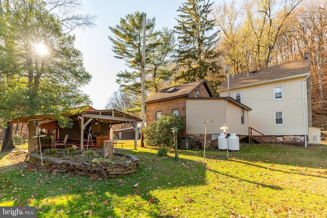 rear view of property featuring a lawn and central air condition unit