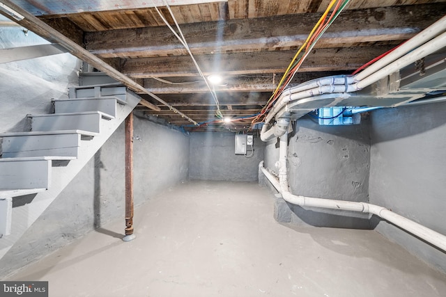unfinished basement with electric panel and stairway
