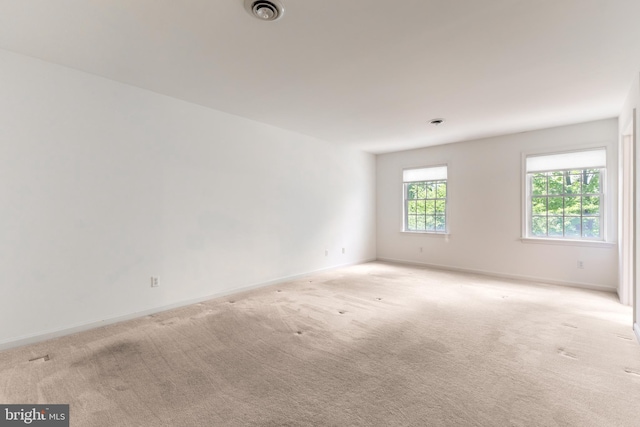 unfurnished room featuring light colored carpet and baseboards