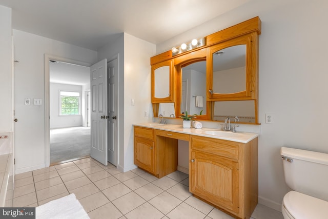 bathroom featuring toilet, double vanity, tile patterned floors, and baseboards
