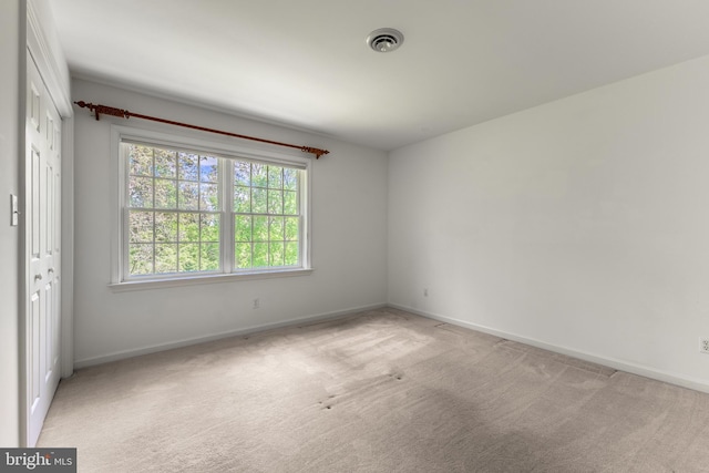 unfurnished room featuring light colored carpet and baseboards