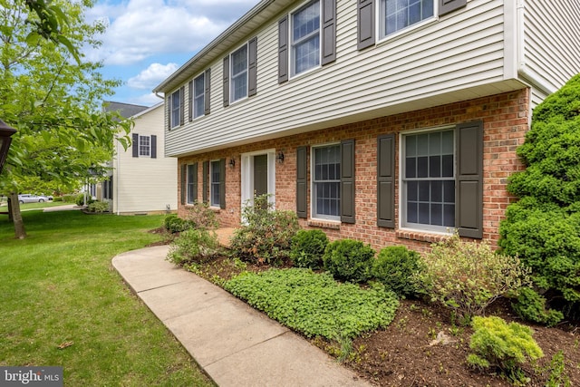 view of side of property with brick siding and a lawn