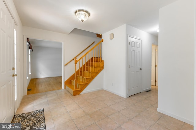 entrance foyer with stairway, light tile patterned floors, and baseboards