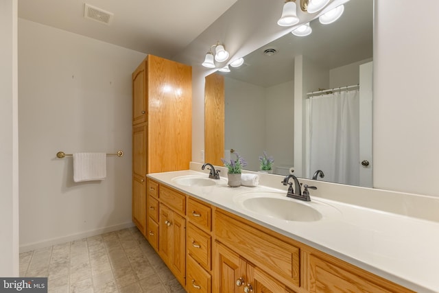 full bath featuring baseboards and double vanity