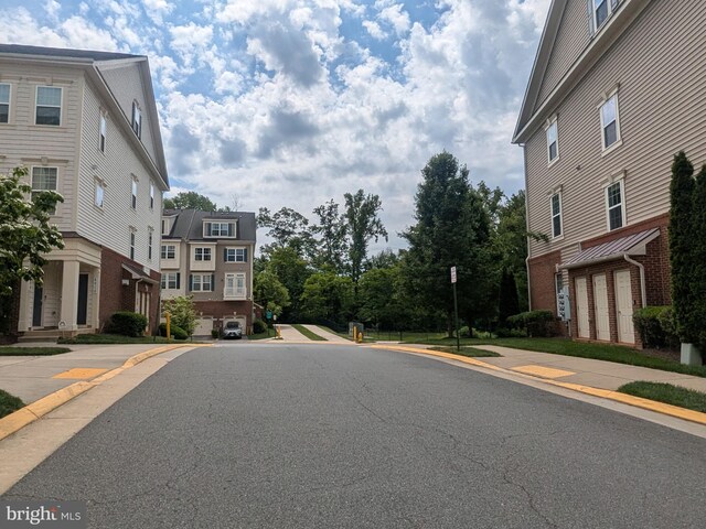 view of asphalt road featuring sidewalks and curbs