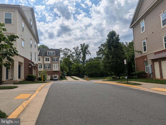 view of asphalt road featuring sidewalks and curbs