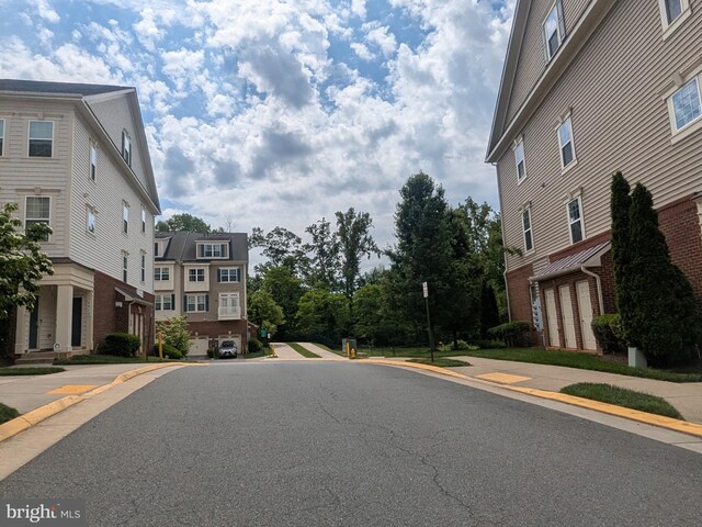 view of asphalt road featuring sidewalks and curbs