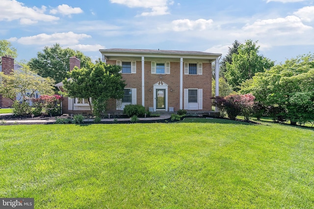 neoclassical / greek revival house with a front yard and brick siding