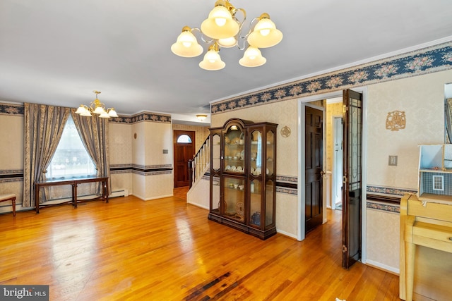 unfurnished dining area with a chandelier, wallpapered walls, light wood finished floors, stairway, and ornamental molding