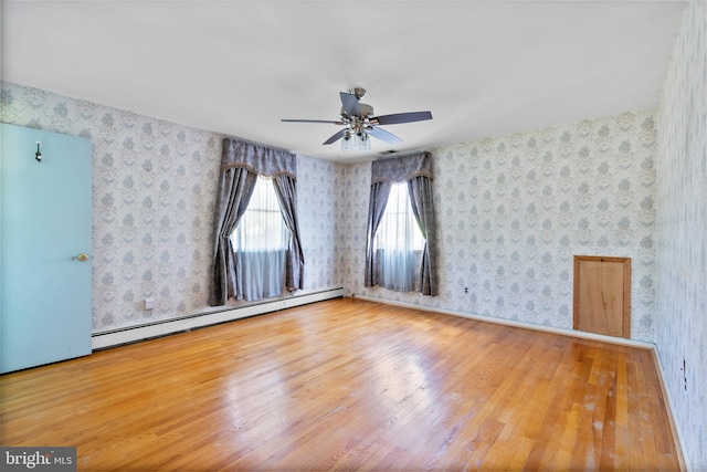unfurnished room with baseboard heating, wood finished floors, a ceiling fan, and wallpapered walls