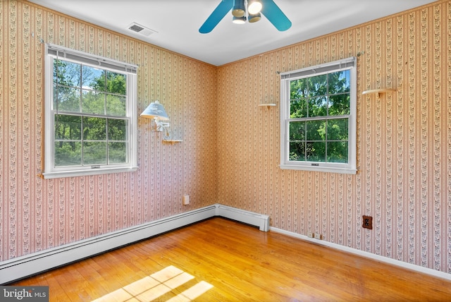 spare room featuring wood finished floors, baseboard heating, ceiling fan, and baseboards