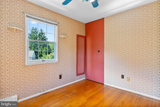 empty room with wood-type flooring, a ceiling fan, baseboards, and crown molding