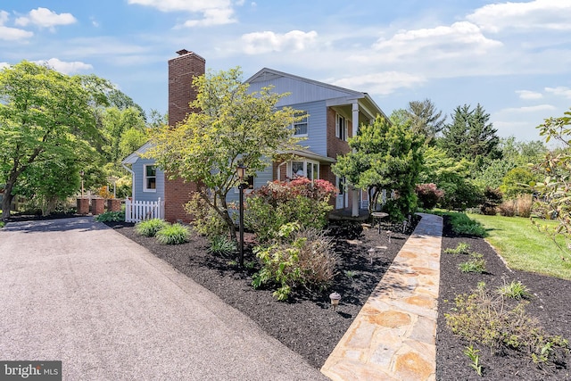 view of front of home featuring a chimney, fence, and brick siding