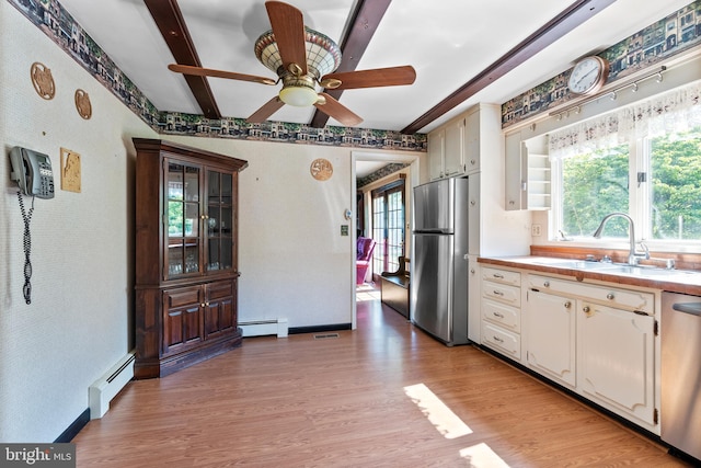 kitchen featuring appliances with stainless steel finishes, a baseboard heating unit, a sink, light wood finished floors, and wallpapered walls
