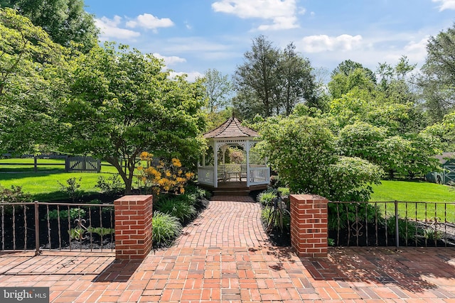 surrounding community with a gazebo and view of wooded area