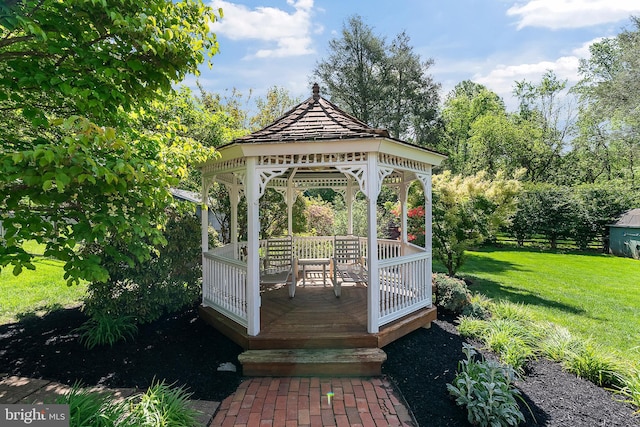 wooden deck featuring a gazebo, a yard, and view of wooded area