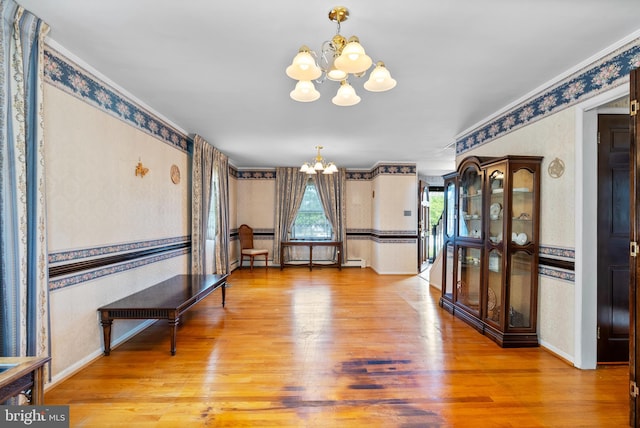 dining space with a chandelier, wallpapered walls, wood finished floors, baseboards, and a baseboard heating unit