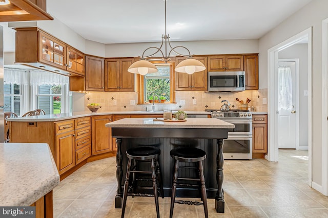 kitchen featuring appliances with stainless steel finishes, light countertops, brown cabinets, and backsplash