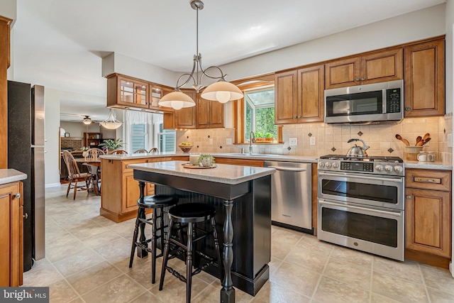 kitchen featuring stainless steel appliances, brown cabinetry, a peninsula, and backsplash