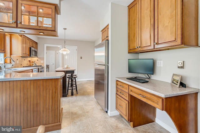 kitchen with stainless steel appliances, brown cabinetry, light tile patterned floors, and a sink