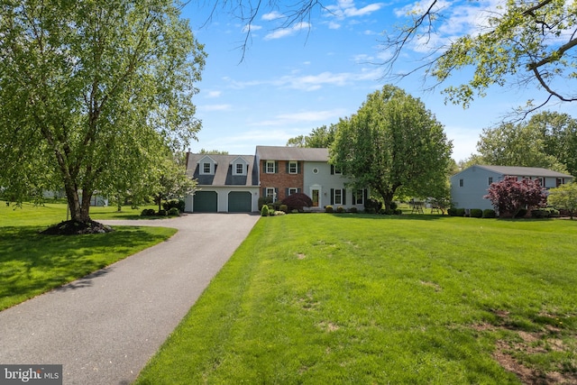 view of front of home featuring asphalt driveway, a front lawn, and a garage