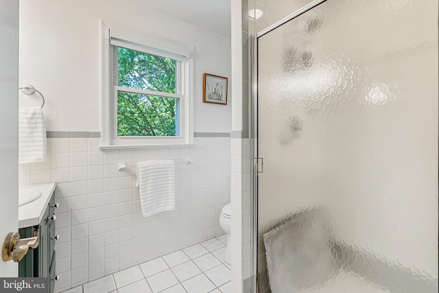 full bath with a shower stall, tile walls, tile patterned floors, a wainscoted wall, and vanity