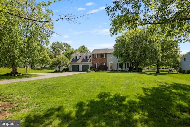 colonial house featuring driveway, a front lawn, and a garage