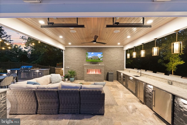 18729 Upper Meadow Dr, Leesburg, VA 20176 - patio terrace at dusk with exterior kitchen, fence, an outdoor living space with a fireplace, a ceiling fan, and area for grilling